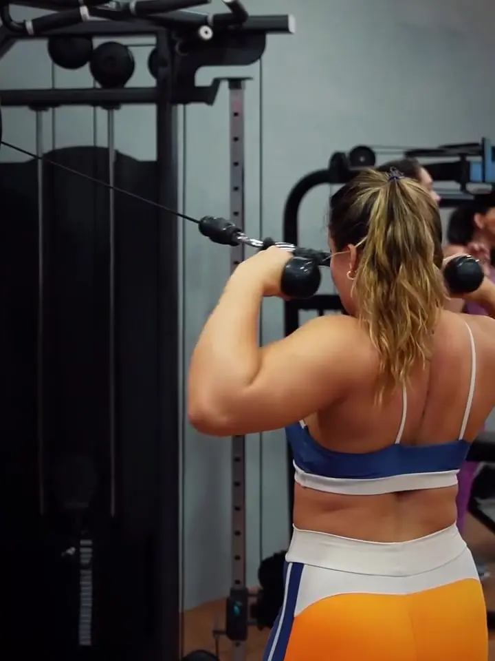 Aluna treinando na polia do salão de musculação da Led Fit